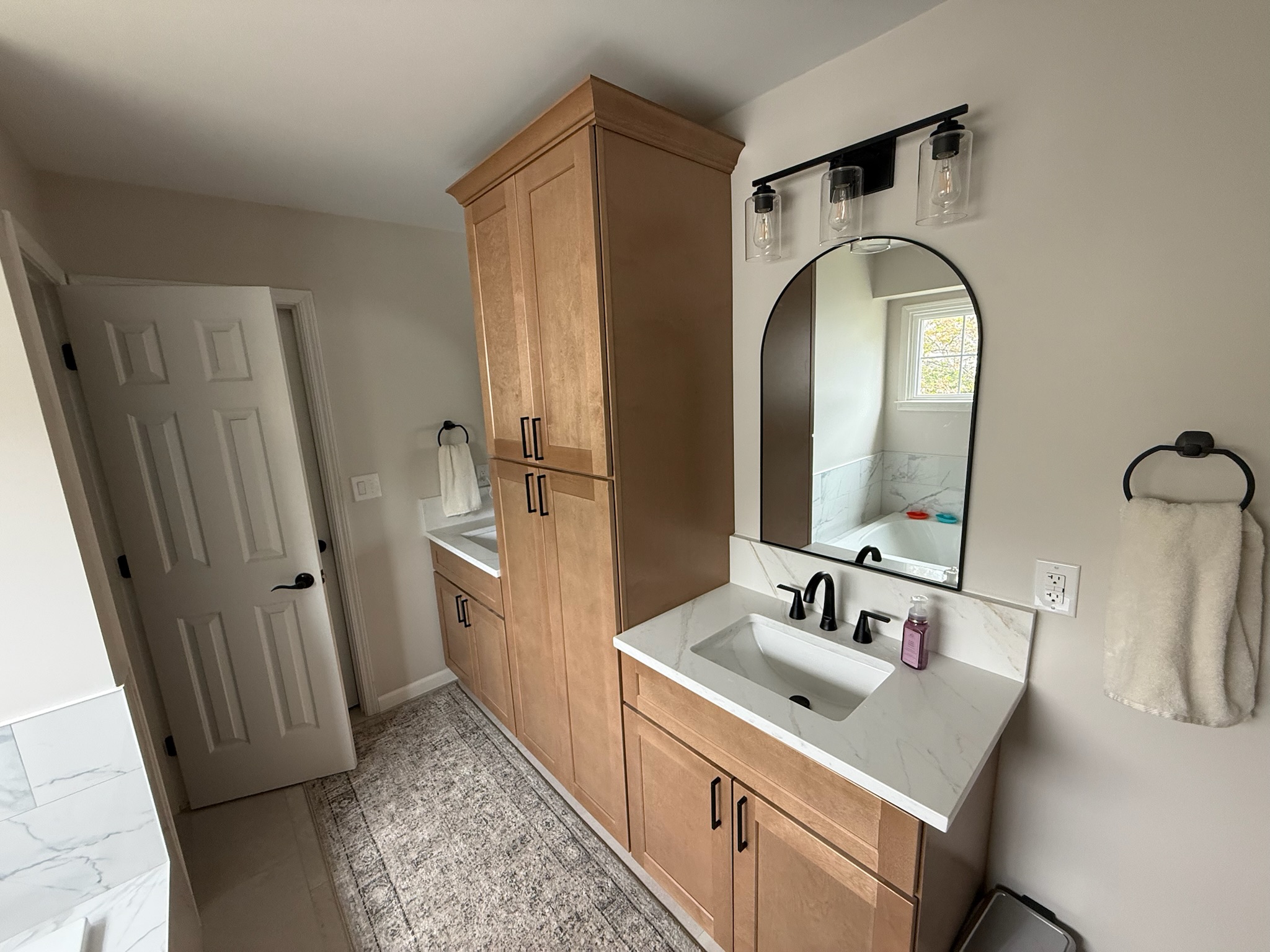 Bathroom vanity with arched mirror and matte black fixtures in Upstate SC