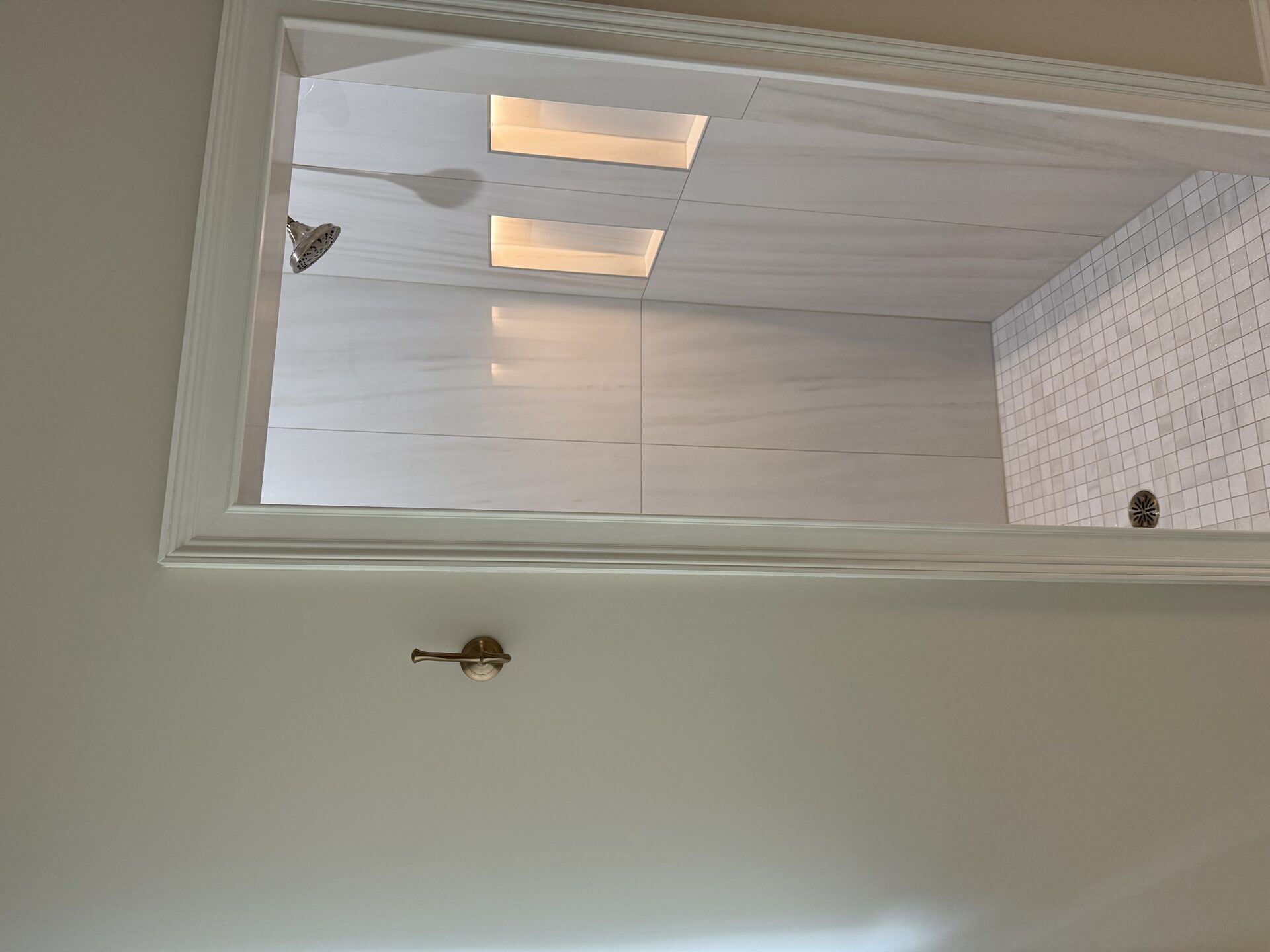 Finished walk-in shower entry in the Marchbanks primary bathroom in Greer, SC - large-format slab walls with lit niches and mosaic tile floor