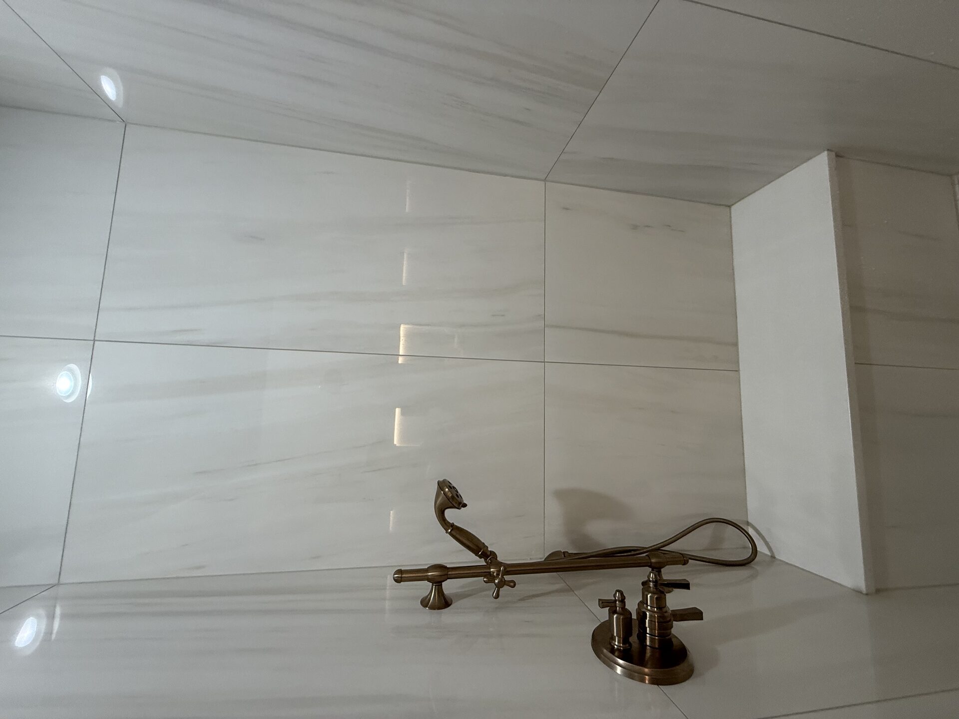 Finished built-in shower bench with brushed gold handheld fixture and thermostatic valve in the Marchbanks primary bathroom in Greer, SC