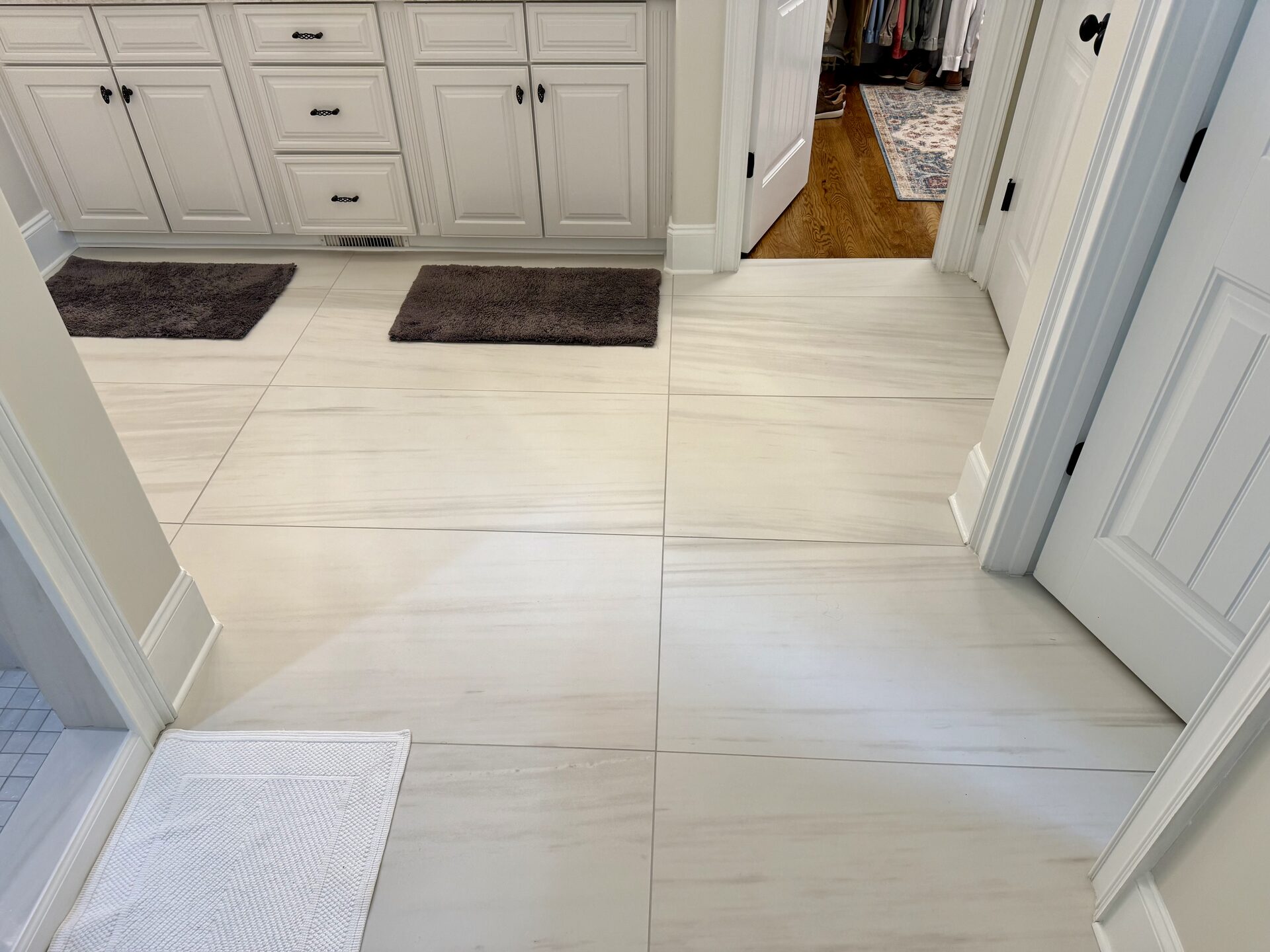Finished large-format stone-look floor tile flowing from the bathroom into the closet in the Marchbanks primary bathroom in Greer, SC