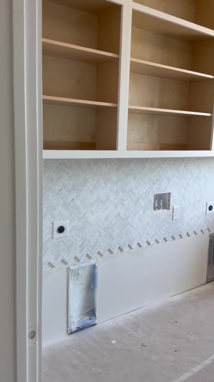 Custom built-in cabinetry with a herringbone marble mosaic backsplash in a high-end Chesnee, SC build