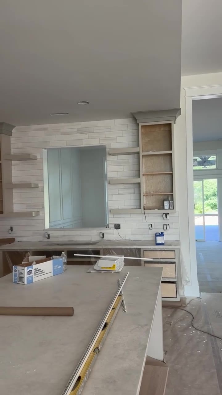 Marble subway tile vanity wall with floating shelves, frameless mirror, and custom cabinetry in a high-end Chesnee, SC build